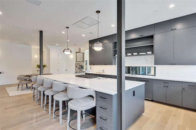 kitchen featuring a large island, hanging light fixtures, gray cabinets, and sink