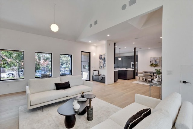 living room with high vaulted ceiling and light hardwood / wood-style floors