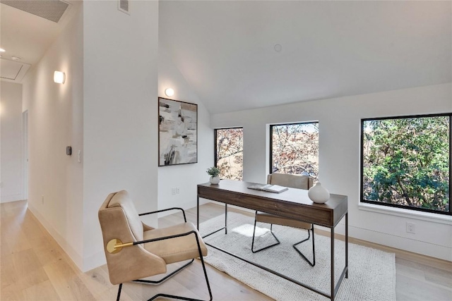 office with lofted ceiling, light hardwood / wood-style floors, and a wealth of natural light