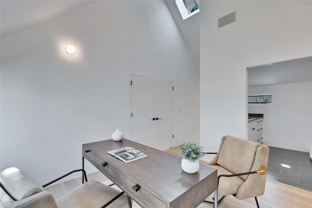 home office featuring a high ceiling and light hardwood / wood-style flooring