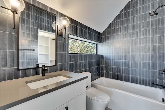 full bathroom with lofted ceiling, tile walls, vanity, tiled shower / bath, and toilet