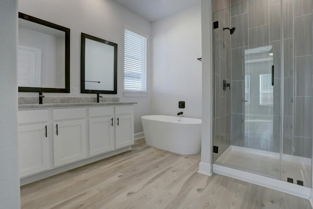 bathroom featuring hardwood / wood-style flooring, vanity, and separate shower and tub