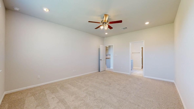 unfurnished bedroom featuring ceiling fan, light colored carpet, and connected bathroom