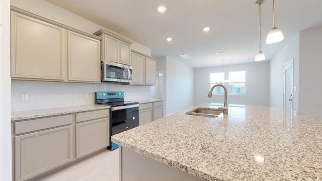 kitchen with sink, appliances with stainless steel finishes, hanging light fixtures, light stone counters, and tasteful backsplash