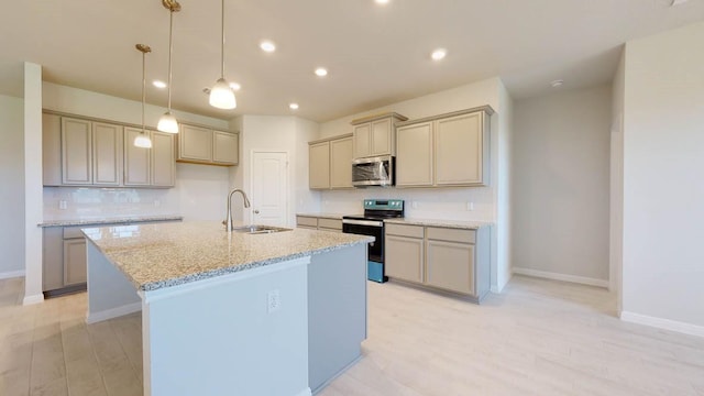 kitchen featuring an island with sink, sink, light stone counters, stainless steel appliances, and light hardwood / wood-style flooring