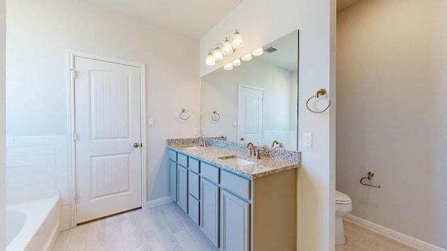 bathroom featuring vanity, a washtub, wood-type flooring, and toilet