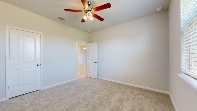 spare room featuring light colored carpet and ceiling fan