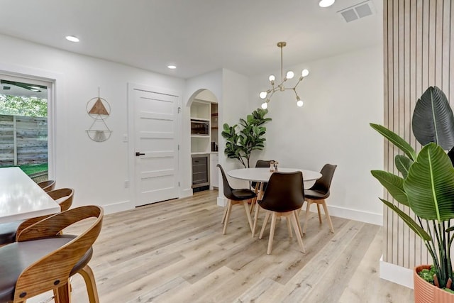 dining area with wine cooler, light hardwood / wood-style flooring, and a chandelier