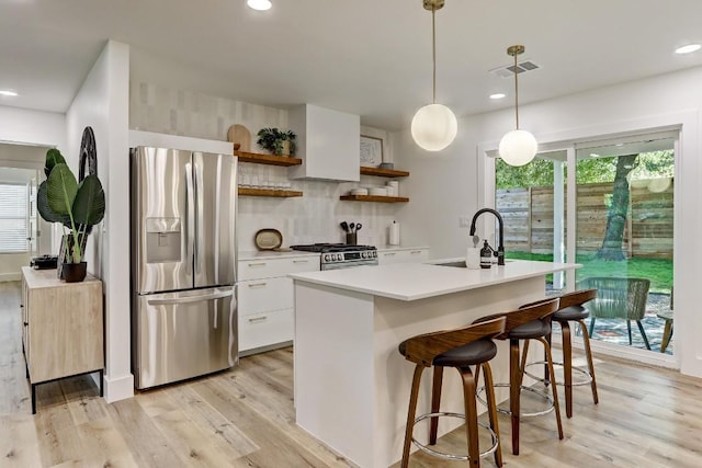 kitchen with sink, white cabinetry, light hardwood / wood-style flooring, appliances with stainless steel finishes, and pendant lighting