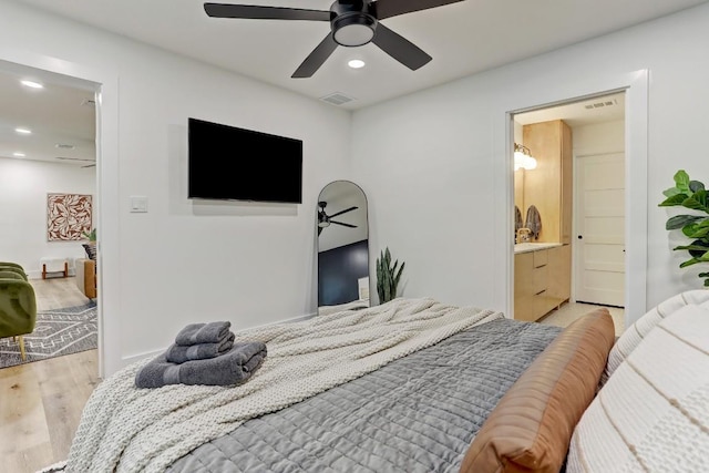 bedroom featuring ceiling fan, ensuite bathroom, and light wood-type flooring