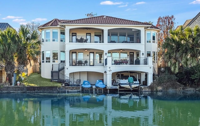 rear view of property featuring a water view, ceiling fan, and a balcony