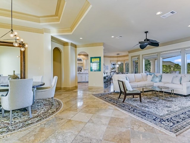 living room with a raised ceiling, crown molding, and ceiling fan with notable chandelier