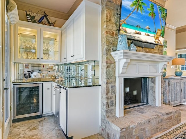 bar featuring white cabinetry, dark stone counters, beverage cooler, and crown molding