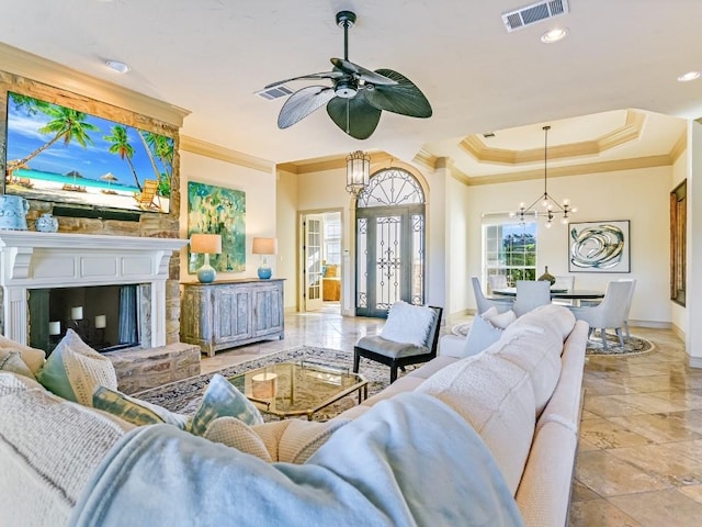 living room with ornamental molding, ceiling fan with notable chandelier, and a tray ceiling