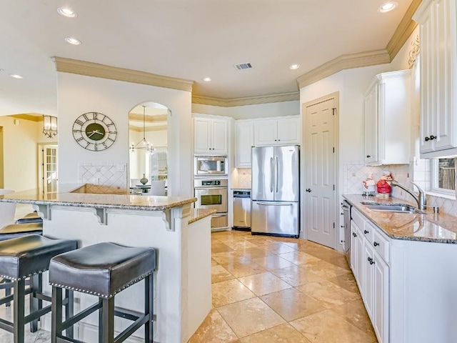 kitchen featuring sink, white cabinetry, kitchen peninsula, stainless steel appliances, and light stone countertops