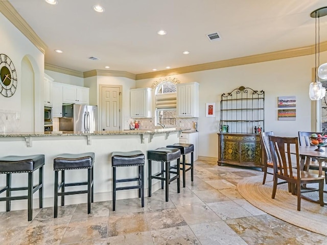 kitchen with light stone counters, tasteful backsplash, stainless steel appliances, and white cabinets