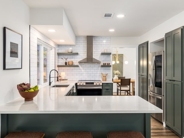 kitchen featuring visible vents, wall chimney exhaust hood, appliances with stainless steel finishes, open shelves, and a sink