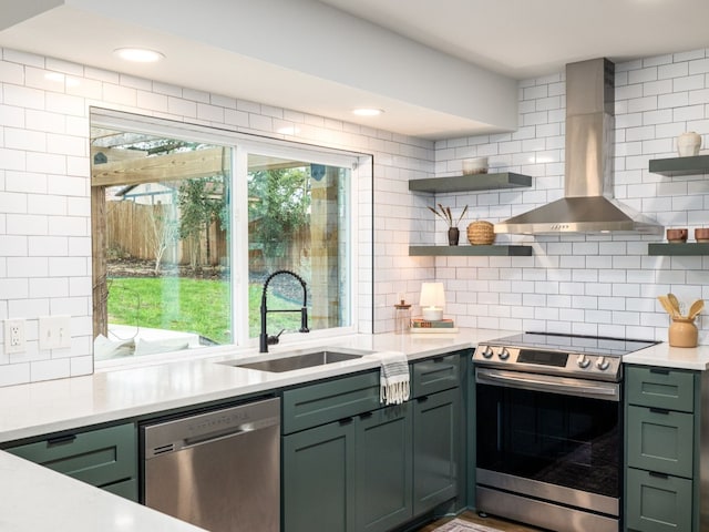 kitchen with a sink, stainless steel appliances, wall chimney range hood, and open shelves