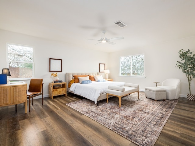 bedroom featuring a ceiling fan, dark wood-style flooring, visible vents, and baseboards