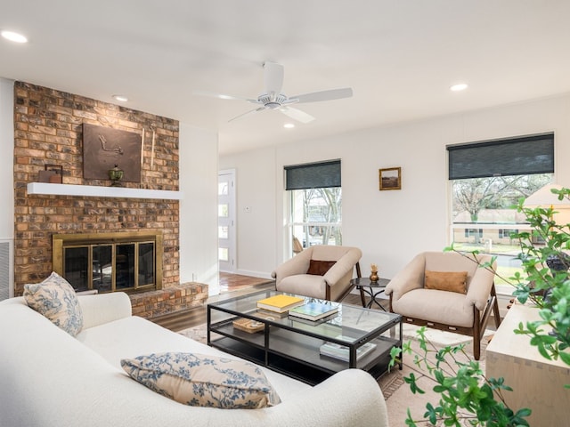 living room featuring hardwood / wood-style flooring, ceiling fan, and a fireplace