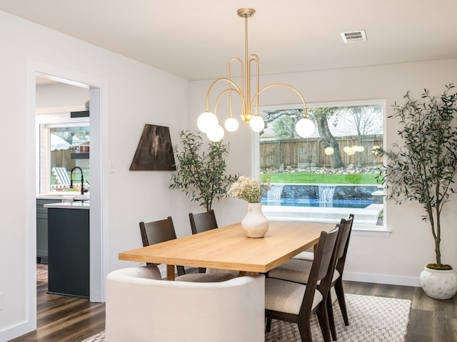 dining room featuring dark wood-type flooring, sink, and a notable chandelier