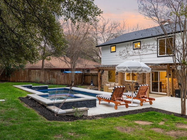 pool at dusk with a yard, a hot tub, and a patio area