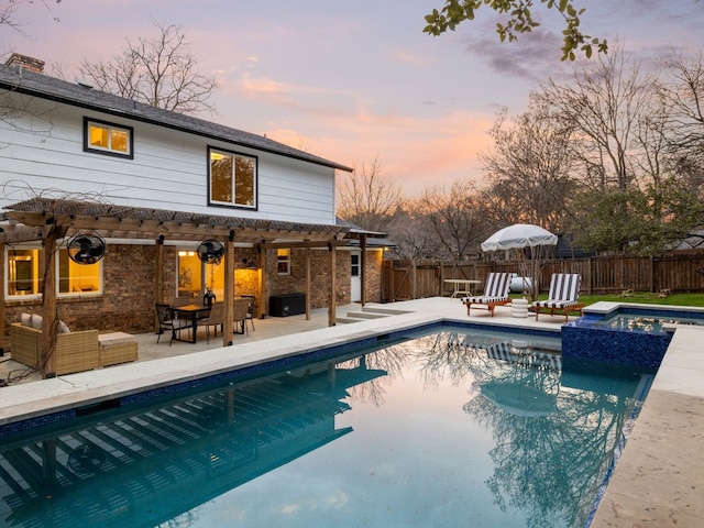 pool at dusk featuring an in ground hot tub, an outdoor hangout area, and a patio