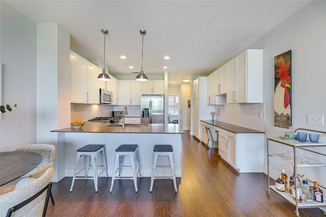 2800 Treble Ln Unit 831, Austin, TX 78704 - kitchen featuring appliances with stainless steel finishes, a peninsula, dark wood-style floors, a breakfast bar, and backsplash