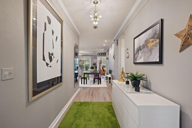 hall with ornamental molding, a notable chandelier, and light hardwood / wood-style floors