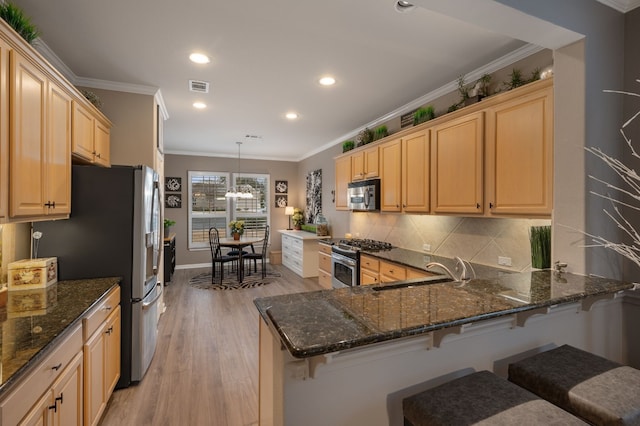 kitchen featuring sink, hanging light fixtures, appliances with stainless steel finishes, kitchen peninsula, and dark stone counters