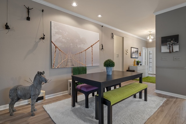 dining space featuring ornamental molding, a notable chandelier, and light hardwood / wood-style flooring