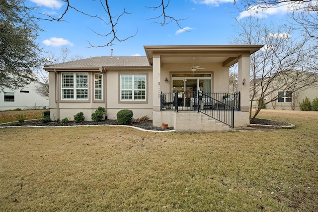 rear view of house with ceiling fan and a yard