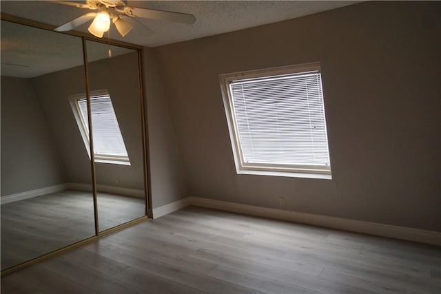 unfurnished bedroom with ceiling fan, a closet, light hardwood / wood-style flooring, and a textured ceiling