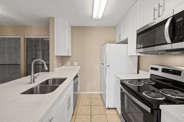 kitchen featuring appliances with stainless steel finishes, sink, light tile patterned floors, a textured ceiling, and white cabinets