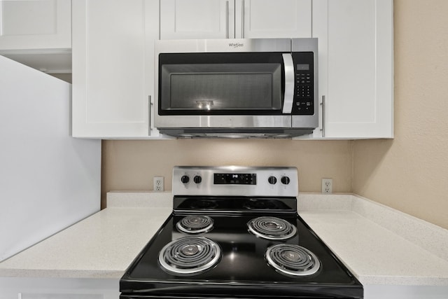 kitchen featuring light stone countertops, white cabinetry, and range with electric stovetop