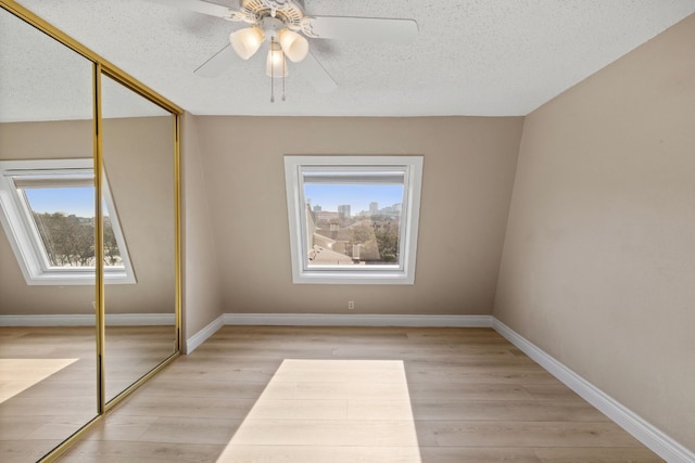 interior space with light hardwood / wood-style floors, a closet, ceiling fan, and a textured ceiling