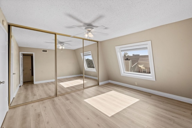 unfurnished bedroom featuring light wood-type flooring, a closet, ceiling fan, and a textured ceiling