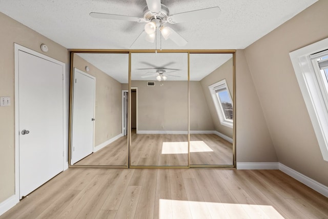 unfurnished bedroom featuring a textured ceiling, a closet, ceiling fan, and light hardwood / wood-style flooring