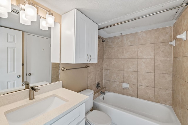 full bathroom featuring tiled shower / bath combo, vanity, toilet, and a textured ceiling