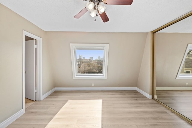 unfurnished bedroom with light hardwood / wood-style flooring, ceiling fan, a closet, and a textured ceiling