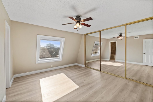 unfurnished bedroom featuring light hardwood / wood-style flooring, ceiling fan, a closet, and a textured ceiling