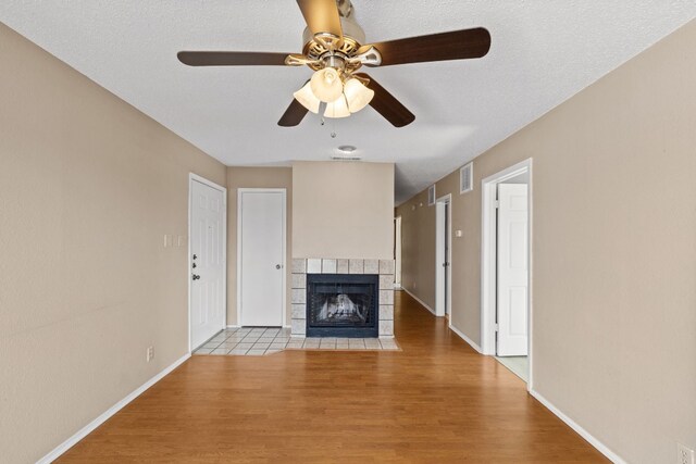 unfurnished living room with a fireplace, hardwood / wood-style floors, a textured ceiling, and ceiling fan