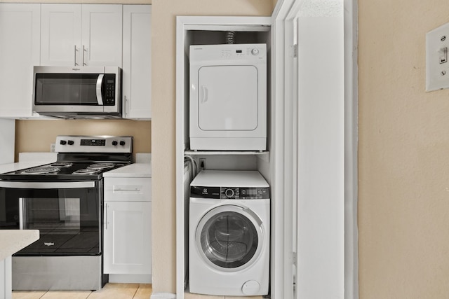 laundry area featuring light tile patterned floors and stacked washing maching and dryer