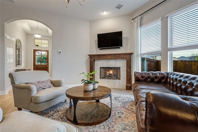 living room featuring a tile fireplace and light wood-type flooring