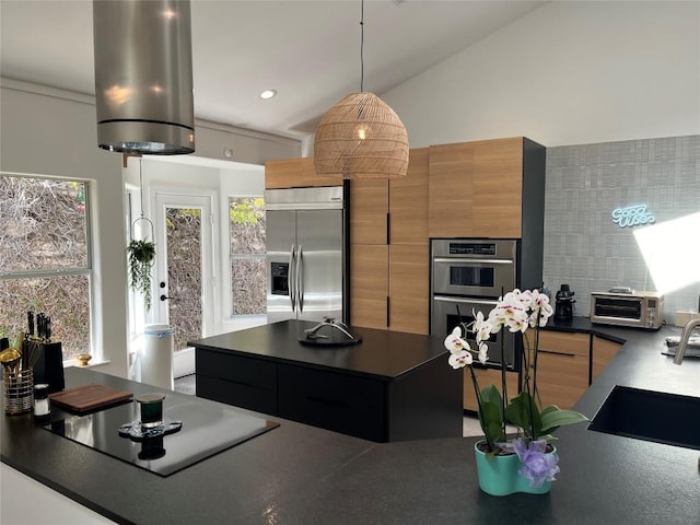 kitchen with vaulted ceiling, stainless steel appliances, decorative light fixtures, and sink