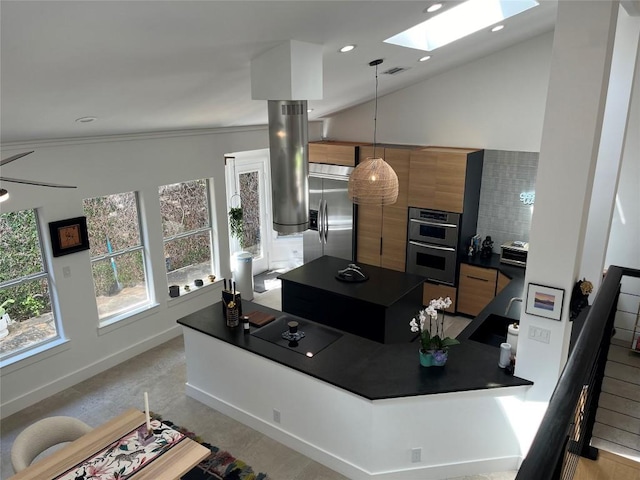 kitchen with pendant lighting, ornamental molding, vaulted ceiling with skylight, and appliances with stainless steel finishes