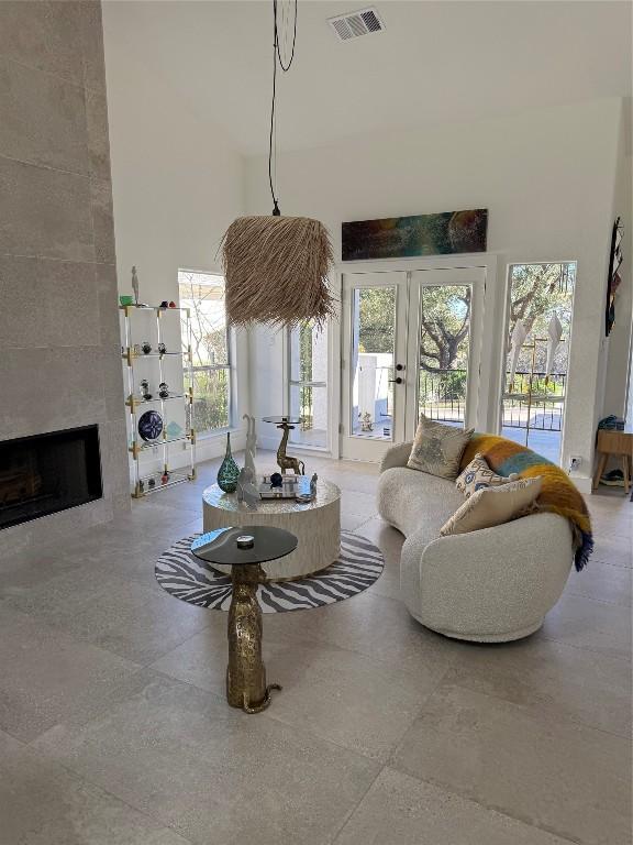 living room featuring a tile fireplace, french doors, and a high ceiling