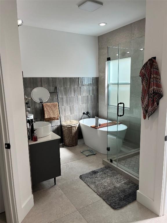 bathroom featuring vanity, shower with separate bathtub, and tile walls