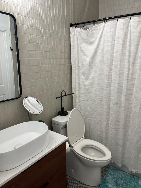 bathroom featuring tile walls, vanity, and toilet