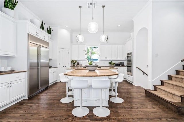 kitchen with appliances with stainless steel finishes, a center island, hanging light fixtures, and white cabinets